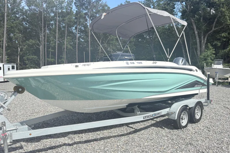 Slide: The Image of 2024 Hurricane SS boat on trailer, parked outdoors with trees in background. - 1