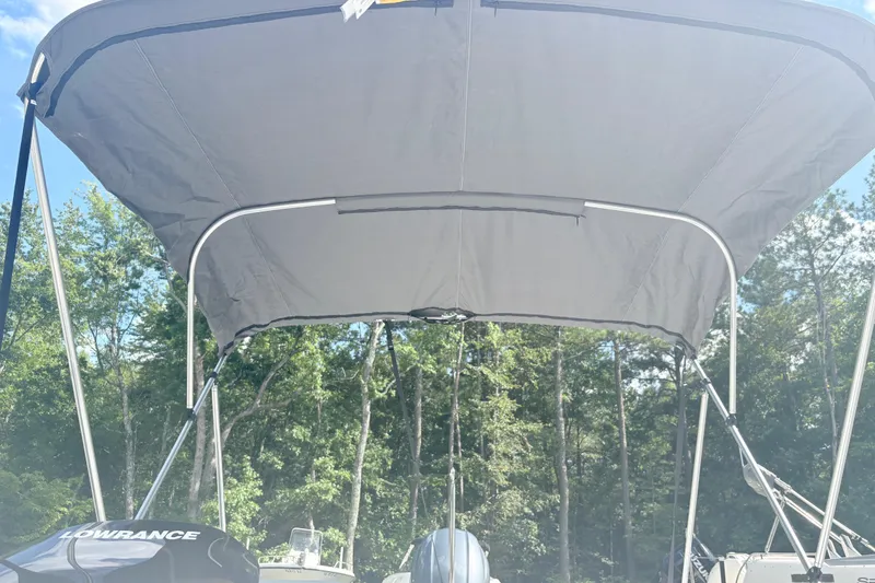 Slide: The Image of 2024 Hurricane SS boat with canopy, featuring Lowrance equipment, surrounded by trees. - 24