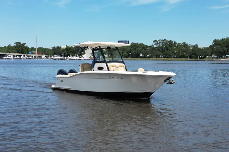 Slide: The Image of 2021 Scout 255 LXF boat cruising on a calm river under a clear blue sky. - 1