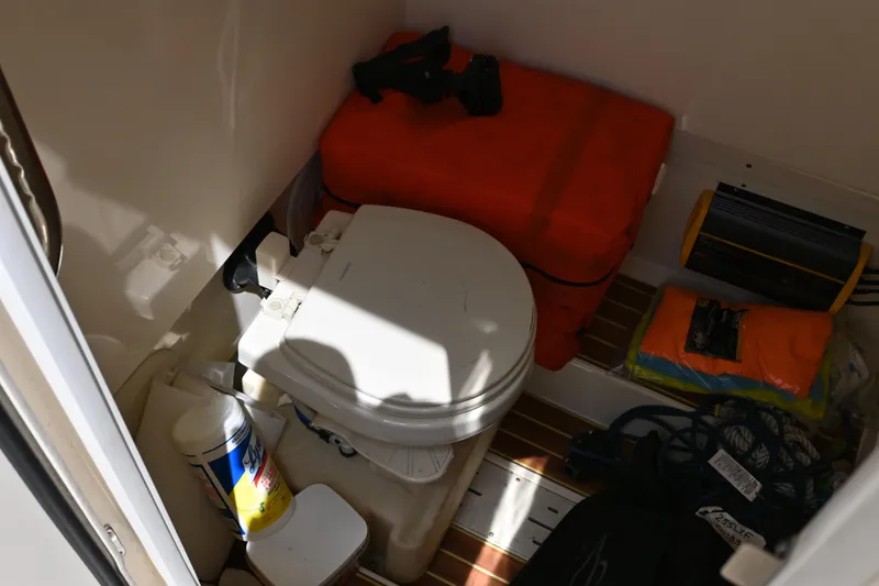 Slide: The Image of Interior of 2021 Scout 255 LXF boat showing compact toilet and storage items. - 12