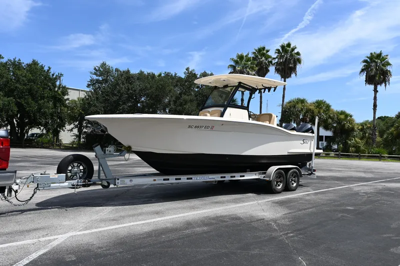 Slide: The Image of 2021 Scout 255 LXF boat on trailer in sunny parking lot with palm trees. - 16