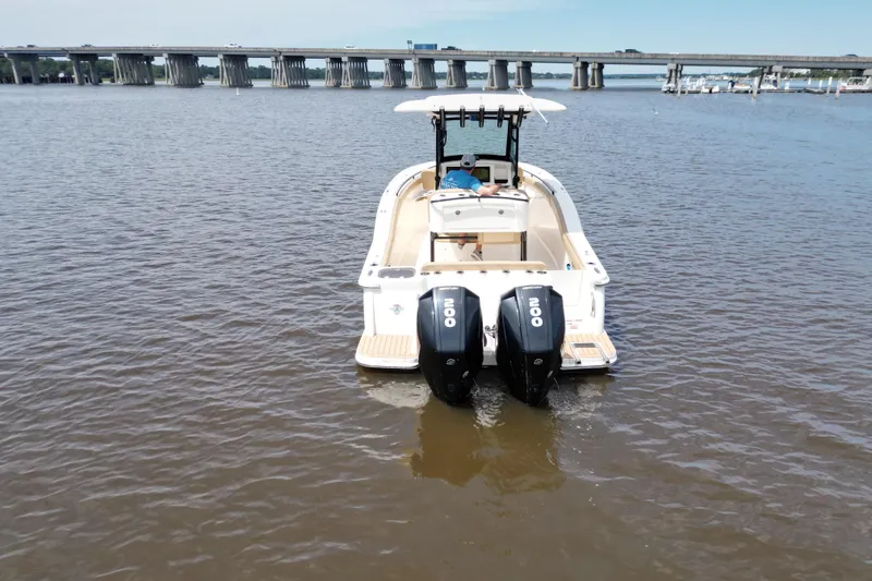 Slide: The Image of 2021 Scout 255 LXF boat with dual engines on calm water near a bridge. - 21