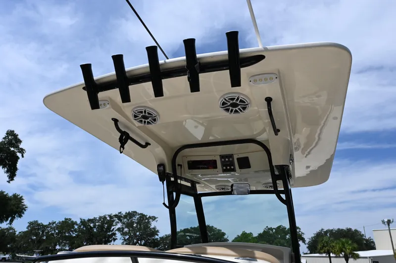 Slide: The Image of 2021 Scout 255 LXF boat T-top with rod holders and speakers under blue sky. - 9