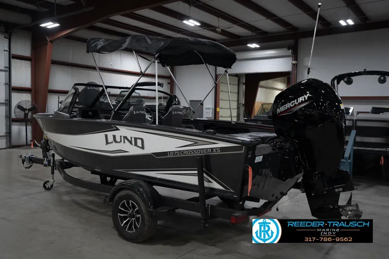 Slide: The Image of 2026 Lund 1875 Crossover XS boat with Mercury engine in indoor showroom. - 10