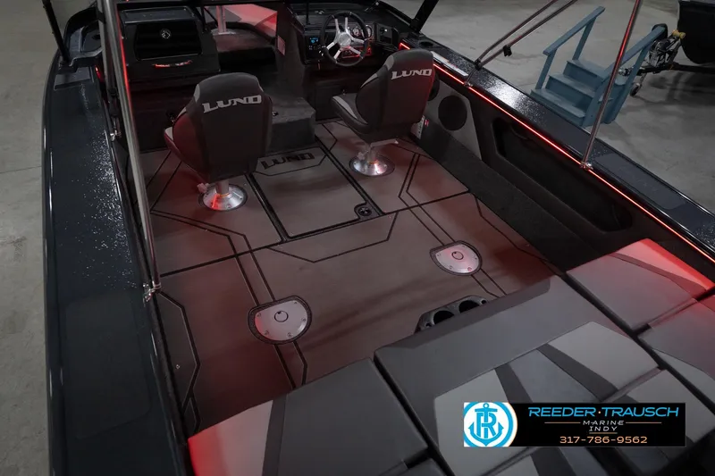 Slide: The Image of 2026 Lund 1875 Crossover XS boat interior with seating and dashboard, featuring red accent lighting. - 14
