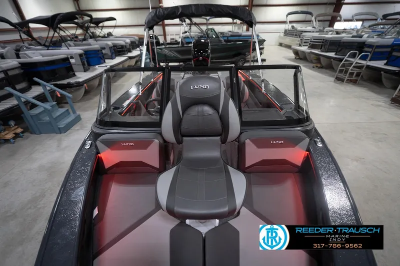 Slide: The Image of 2026 Lund 1875 Crossover XS boat interior in showroom, featuring sleek seating and modern design. - 18