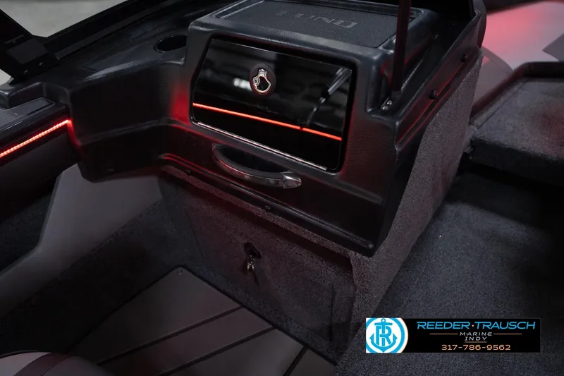 Slide: The Image of 2026 Lund 1875 Crossover XS boat interior with storage compartment and red accent lighting. - 23