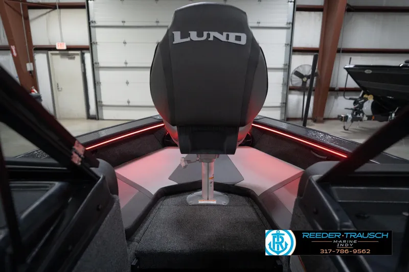 Slide: The Image of 2026 Lund 1875 Crossover XS boat interior with red LED lighting in a garage. - 29