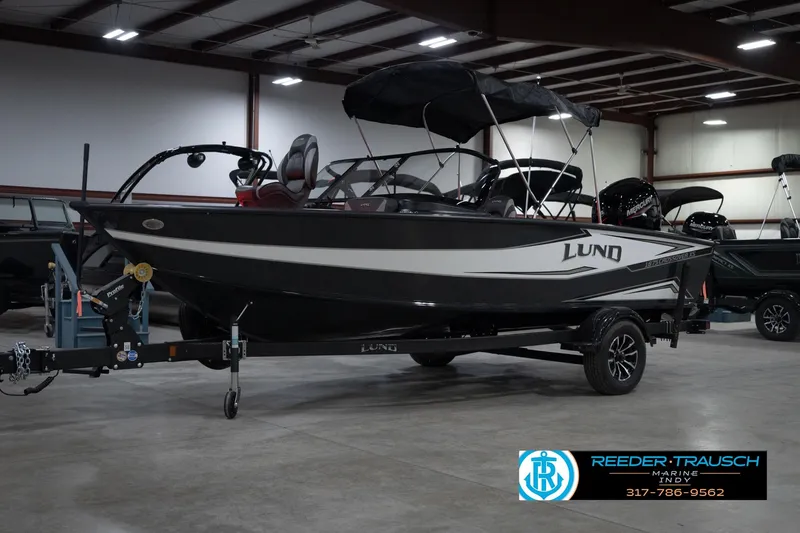Slide: The Image of 2026 Lund 1875 Crossover XS boat in showroom, black and white design, on trailer. - 4