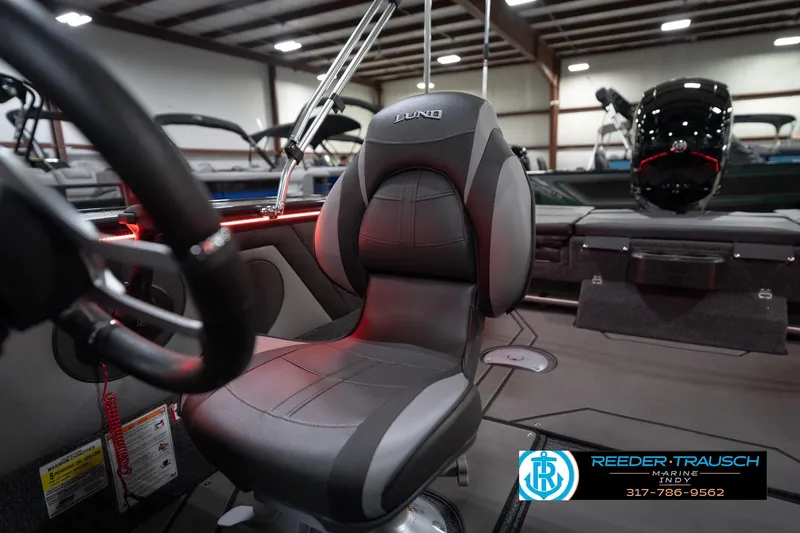 Slide: The Image of 2026 Lund 1875 Crossover XS boat interior with steering wheel and seat in showroom. - 43