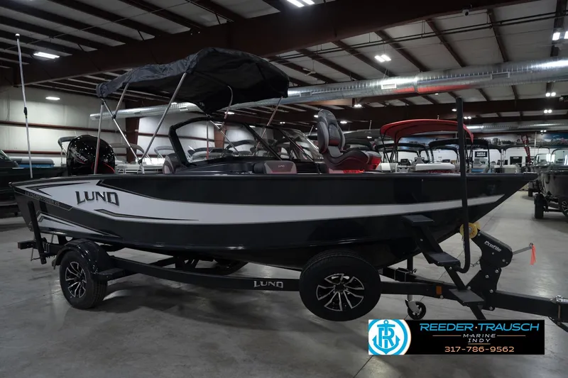 Slide: The Image of 2026 Lund 1875 Crossover XS boat in showroom, black and white design, on trailer. - 6