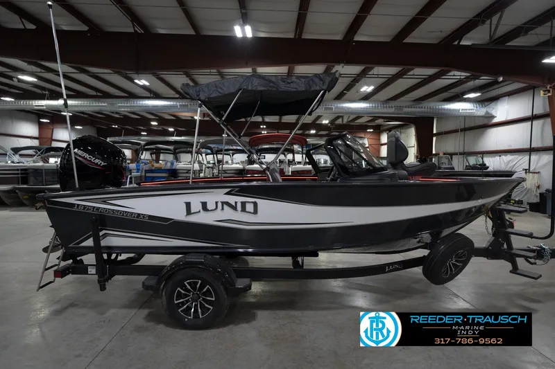 Slide: The Image of 2026 Lund 1875 Crossover XS boat in showroom, side view with trailer. - 7
