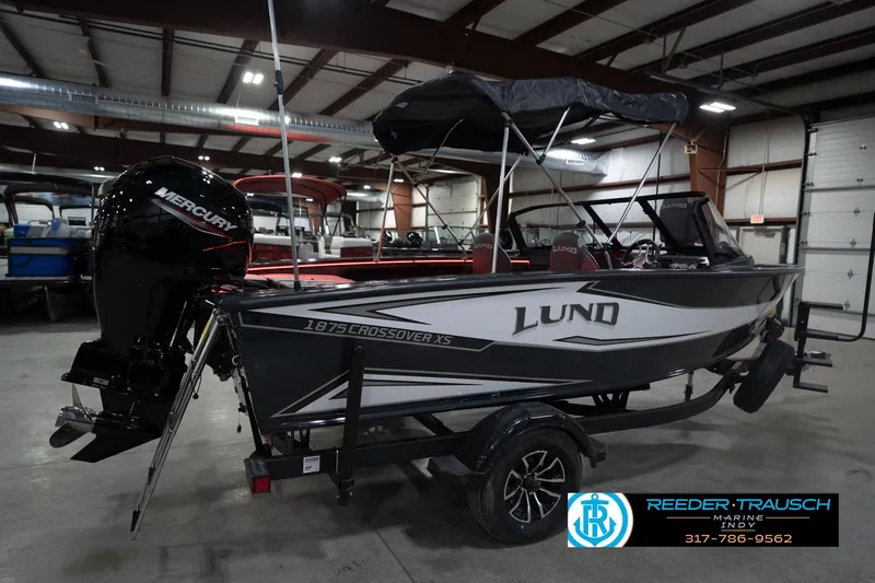 Slide: The Image of 2026 Lund 1875 Crossover XS boat with Mercury engine in indoor showroom. - 8