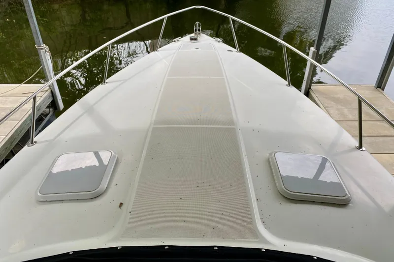 Slide: The Image of 2005 Formula 330 Sun Sport boat deck with railing and hatches, docked by calm water. - 2