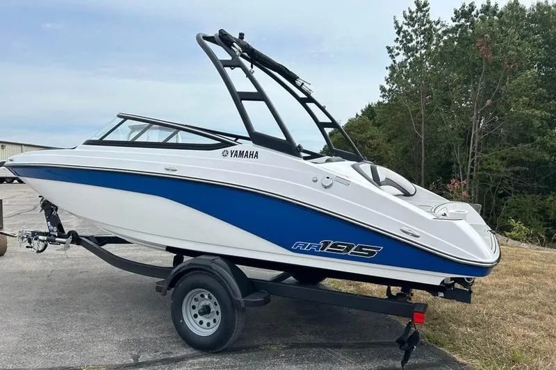 Slide: The Image of 2026 Yamaha AR195 boat on trailer, blue and white design, parked outdoors. - 2