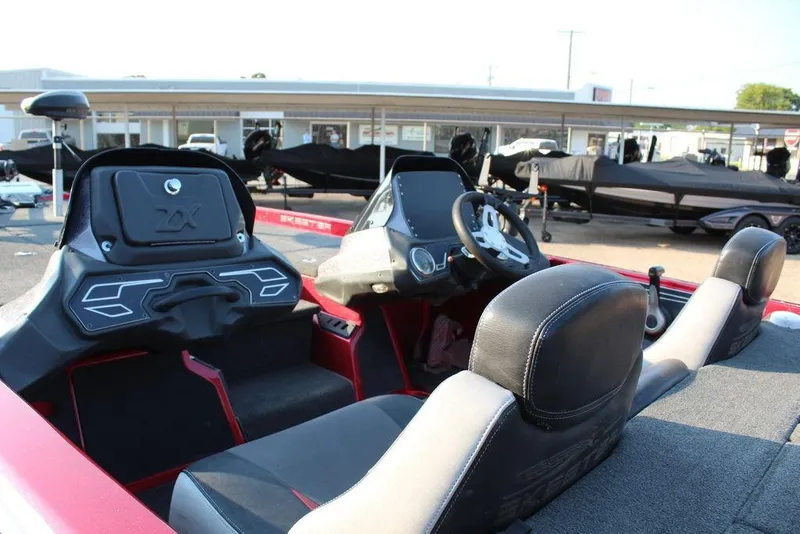 Slide: The Image of 2016 Skeeter ZX250 boat interior with steering wheel and seating, parked outdoors. - 14