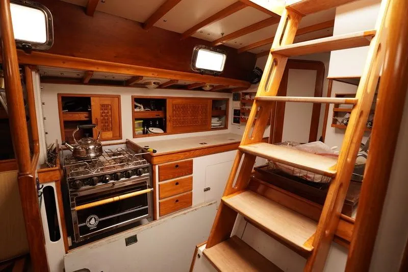 Slide: The Image of Interior of 1993 Brooklin Boat Yard Marshall 48, featuring wooden cabinetry and a compact kitchen. - 11