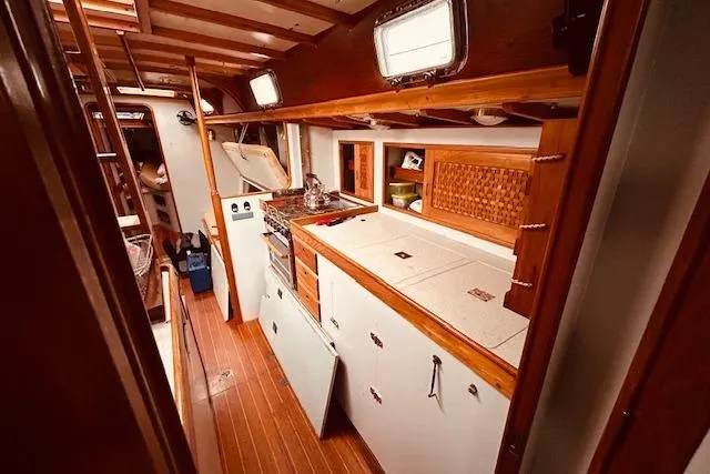 Slide: The Image of Interior of 1993 Brooklin Boat Yard Marshall 48, featuring a well-equipped galley with wooden accents. - 14