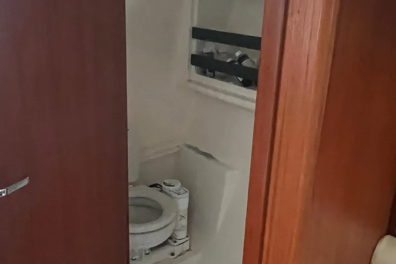 Slide: The Image of 2001 Pursuit 3000 Offshore boat bathroom with wooden door and compact toilet. - 8