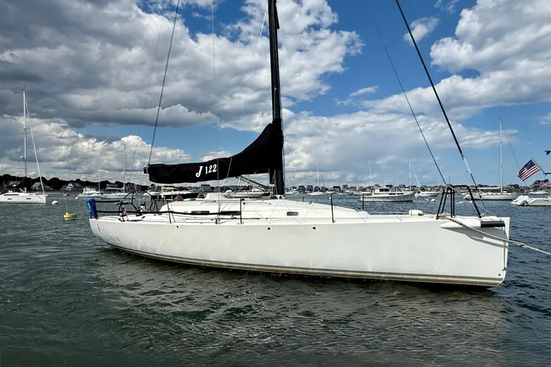 The Image of 2013 J Boats J/122 sailboat anchored in a scenic harbor under a partly cloudy sky. - 1