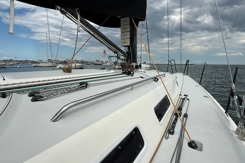 Slide: The Image of 2013 J Boats J/122 sailboat deck with rigging, moored in a marina under cloudy skies. - 29