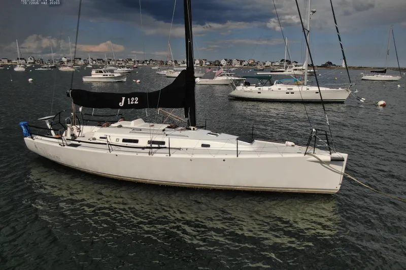 Slide: The Image of 2013 J Boats J/122 sailboat moored in a scenic harbor with other vessels. - 5