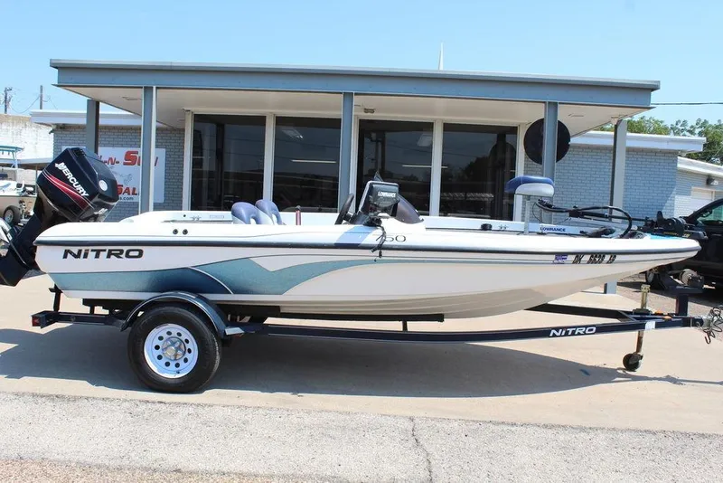 Slide: The Image of 2006 Nitro NX 750 boat on trailer, parked outside a building. - 2