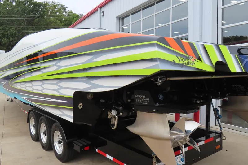 Slide: The Image of 2022 MTI 48 boat with vibrant, colorful design on trailer outside a building. - 3