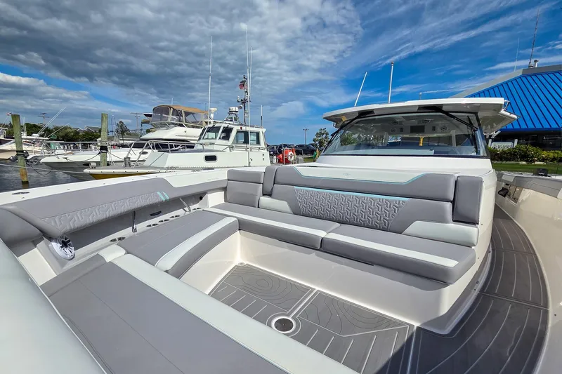 Slide: The Image of 2025 Regal 50 SAV luxury yacht interior with modern seating, docked at marina under blue sky. - 26