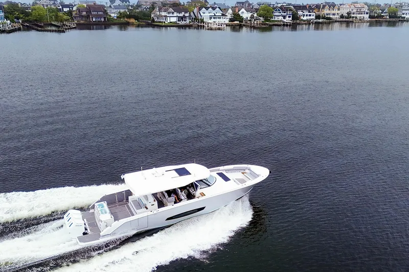 Slide: The Image of 2025 Regal 50 SAV yacht cruising on a serene lake near waterfront homes. - 5