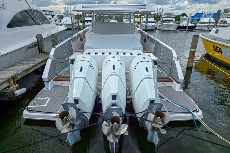 Slide: The Image of 2025 Regal 50 SAV luxury boat with triple outboard engines docked at marina. - 9