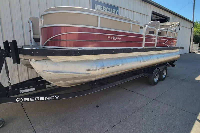 The Image of 2019 Sun Tracker Party Barge 24 DLX pontoon boat on trailer, parked outside a building. - 0