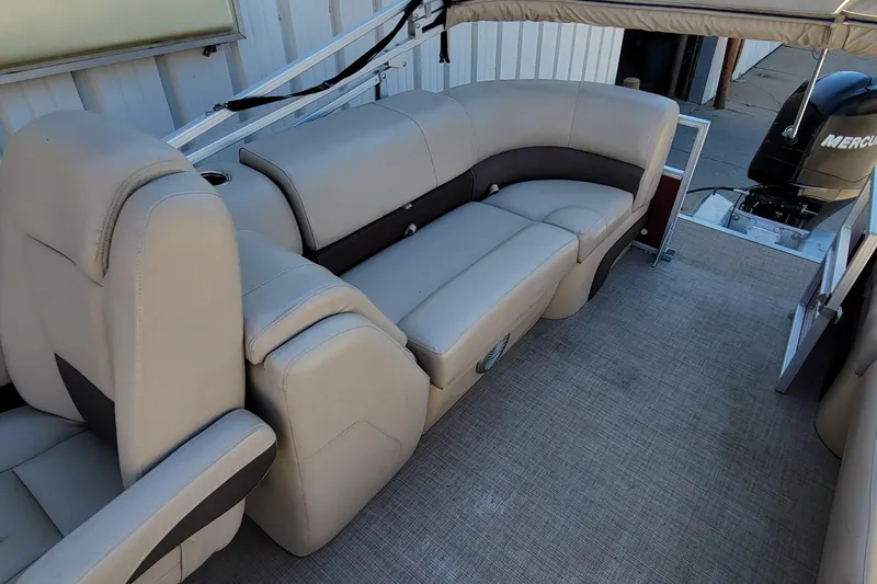Slide: The Image of 2019 Sun Tracker Party Barge 24 DLX beige seating, outdoor setting, trailer in background. - 17