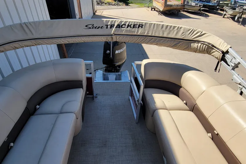 Slide: The Image of 2019 Sun Tracker Party Barge 24 DLX interior with beige captain's chair and steering console. - 19