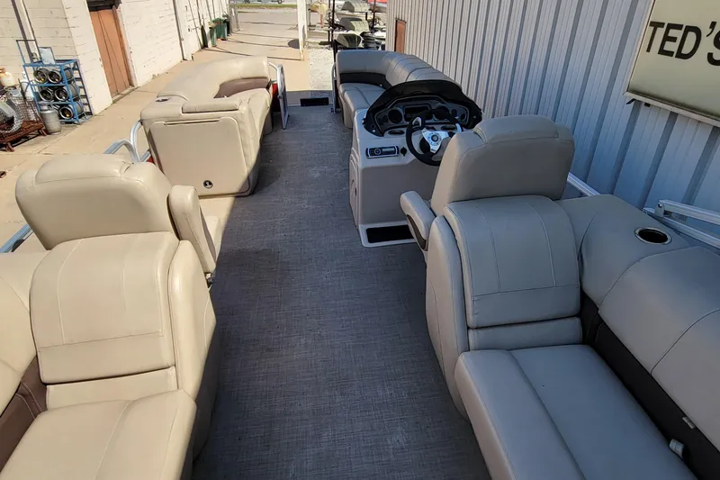 Slide: The Image of 2019 Sun Tracker Party Barge 24 DLX interior with beige seating and steering console. - 34
