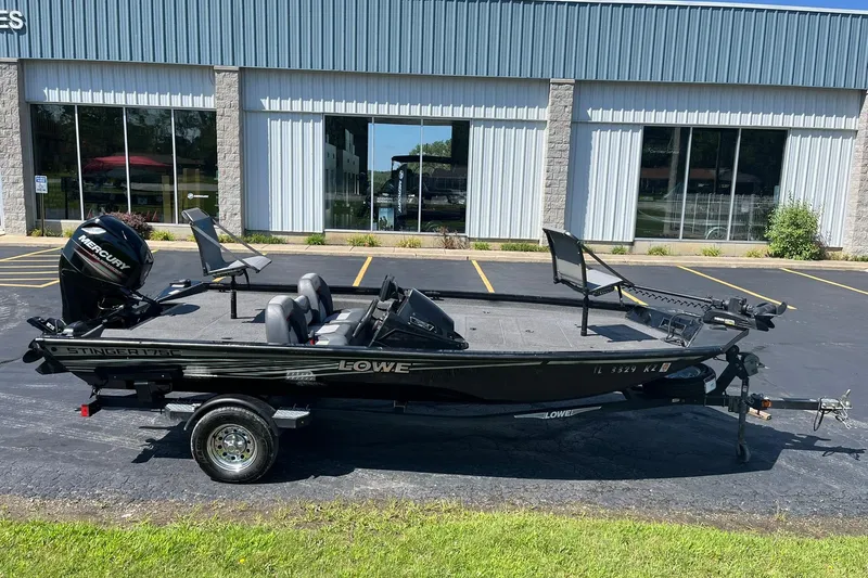 Slide: The Image of 2019 Lowe Stinger 175C fishing boat with Mercury engine, parked outside a building. - 2