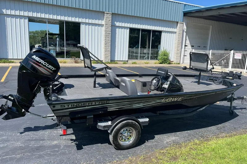 Slide: The Image of 2019 Lowe Stinger 175C fishing boat with Mercury outboard motor, parked outside a building. - 3