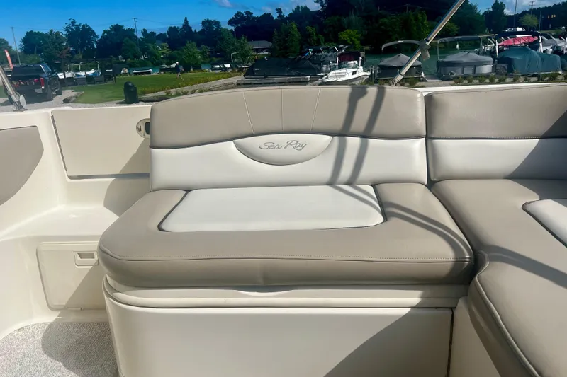 Slide: The Image of 2003 Searay 220 Sundeck boat interior with beige and white seating, docked near a marina. - 11