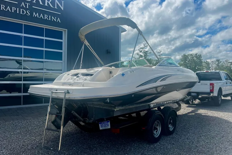 Slide: The Image of 2003 Searay 220 Sundeck boat on trailer at marina, under cloudy sky. - 3