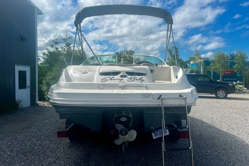 Slide: The Image of 2003 Searay 220 Sundeck boat with canopy, parked on gravel under a blue sky. - 4