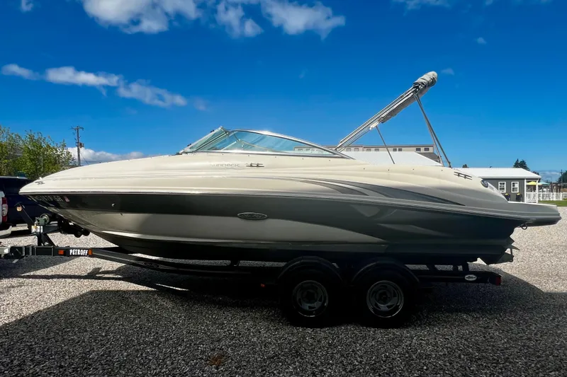 Slide: The Image of 2003 Searay 220 Sundeck boat on trailer under clear blue sky. - 6