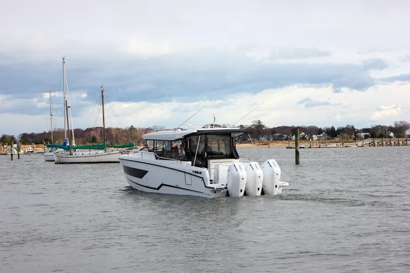 Slide: The Image of 2026 Wellcraft 38 Explorer boat cruising on a calm waterway with sailboats nearby. - 48