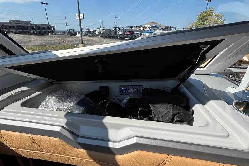 Slide: The Image of Open storage compartment in 2025 Tigé Ultré 25ZX boat, showing battery switch and accessories. - 15
