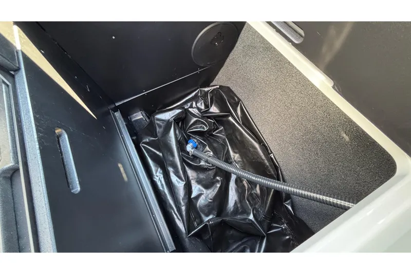 Slide: The Image of Storage compartment of 2025 Tigé Ultré 25ZX boat with black lining and hose. - 39