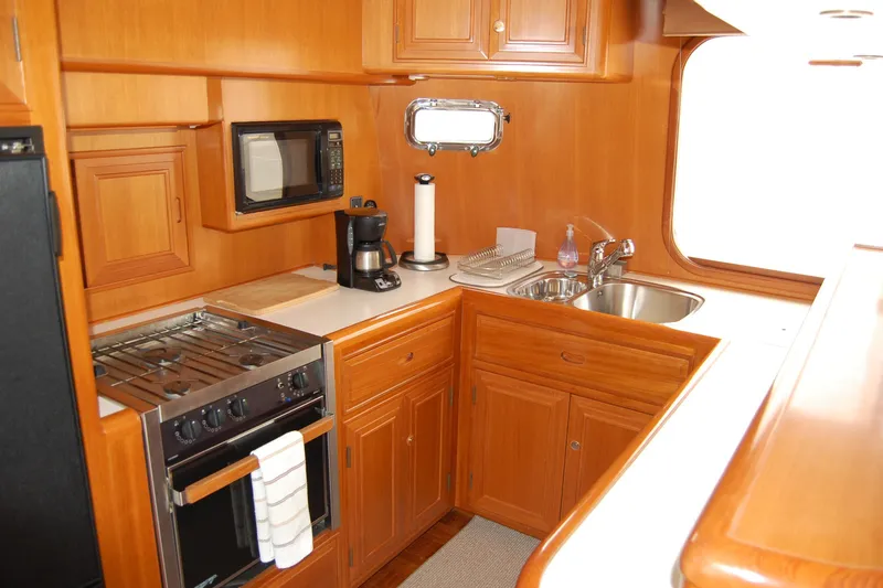 Slide: The Image of 2001 Ocean Alexander Classico yacht kitchen with wood cabinetry, stove, microwave, and sink. - 23