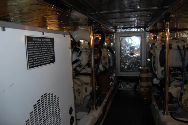 Slide: The Image of Engine room of 2001 Ocean Alexander Classico yacht, featuring machinery and safety signage. - 74