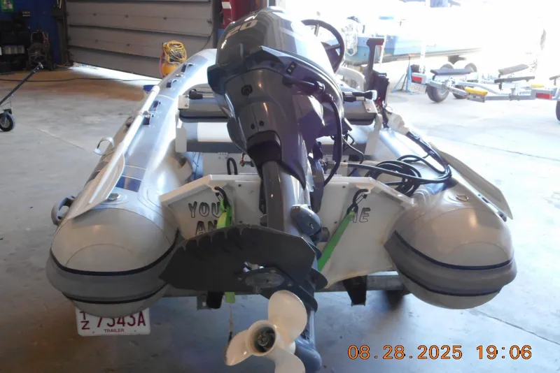 Slide: The Image of 2024 Highfield CL310 inflatable boat with outboard motor in a garage setting. - 4