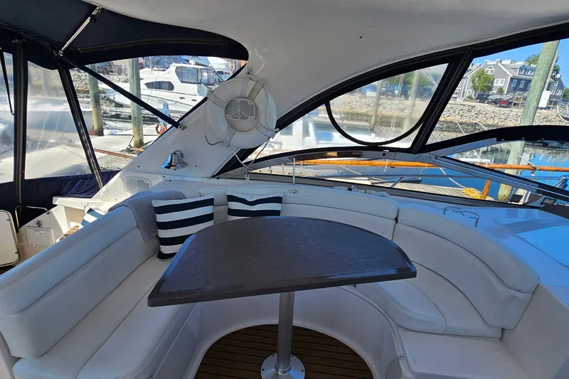 Slide: The Image of 2005 Regal Commodore 4260 yacht interior with curved seating and table, docked at marina. - 12