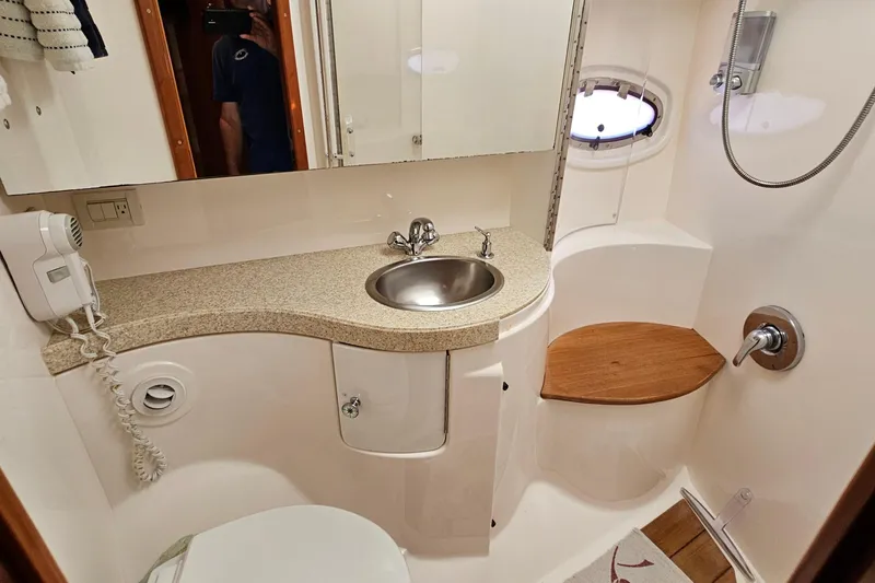 Slide: The Image of Luxurious 2005 Regal Commodore 4260 yacht bathroom with sink, shower, and wooden seat. - 25