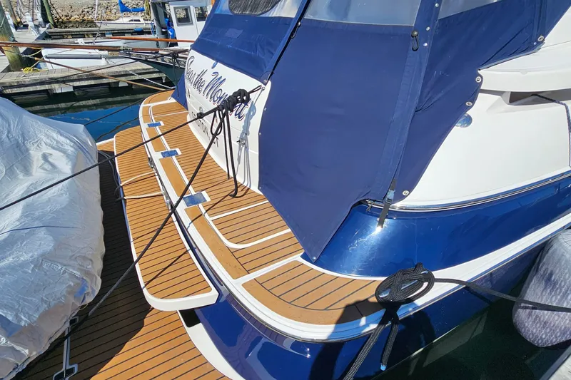 Slide: The Image of 2005 Regal Commodore 4260 yacht with blue cover and wooden deck at marina. - 5